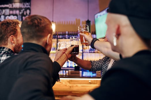 Cheering by knocking beer glasses. Group of people together indoors in the pub have fun at weekend time photo