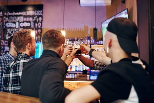 Cheering by knocking beer glasses. Group of people together indoors in the pub have fun at weekend time photo