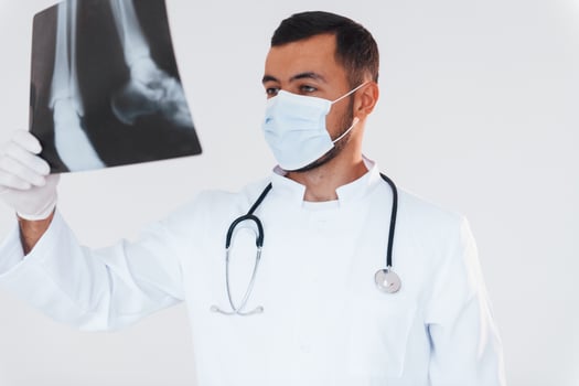 Medic with x-ray. Young handsome man standing indoors against white background photo