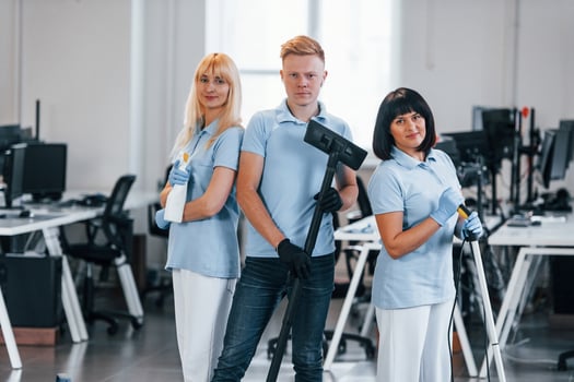 Guy with vacuum cleaner. Group of workers clean modern office together at daytime photo