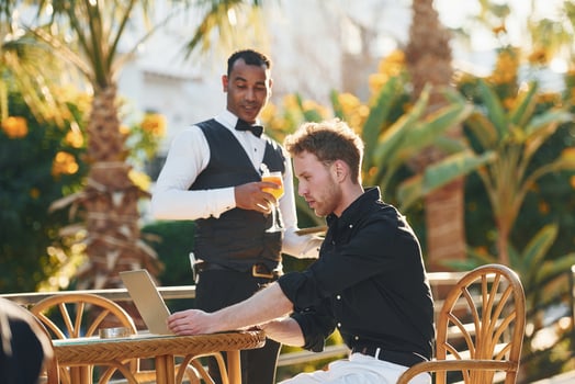 Serviced by waiter. Young man is outdoors at sunny daytime. Concept of vacation photo