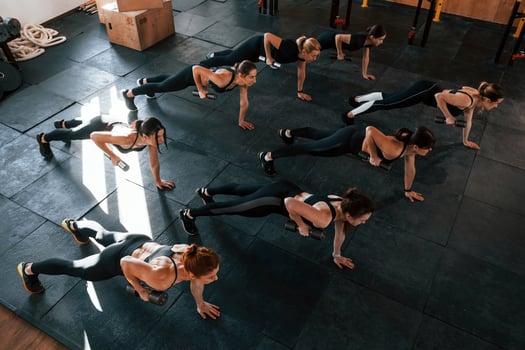 Using barbells. Group of young sportive people have crossfit day indoors in gym photo