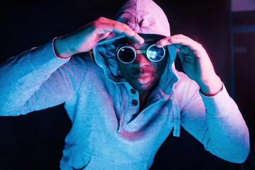 Cyberpunk style glasses. Futuristic neon lighting. Young african american man in the studio photo