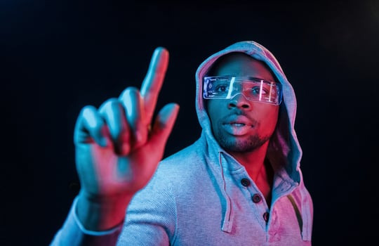 In special eyewear. Futuristic neon lighting. Young african american man in the studio photo