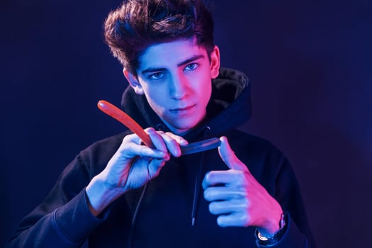 Young barber with work equipment standing in the studio with neon lighting photo