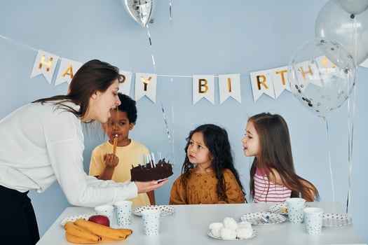 Woman holds cake. Children on celebrating birthday party indoors have fun together photo