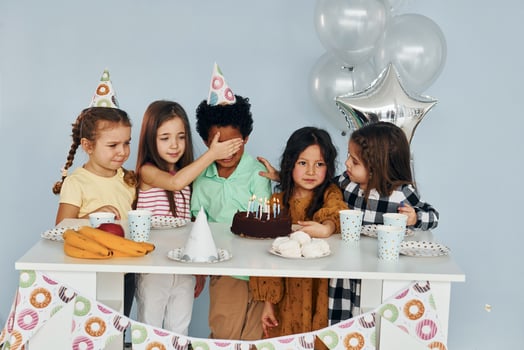 Sits by the table. Children on celebrating birthday party indoors have fun together photo