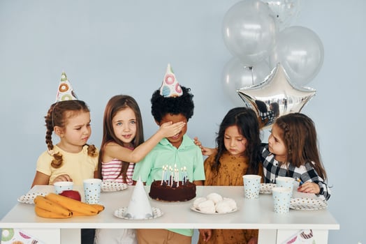 Sits by the table. Children on celebrating birthday party indoors have fun together photo