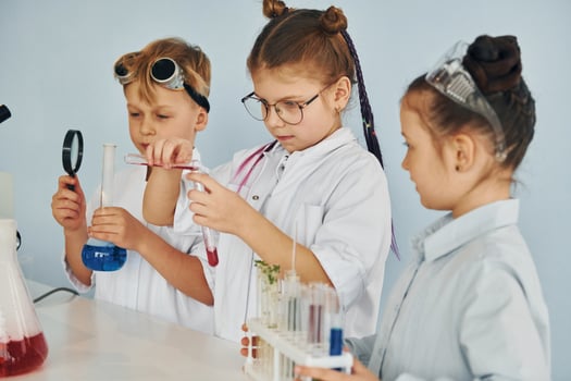 Children in white coats plays a scientists in lab by using equipment photo