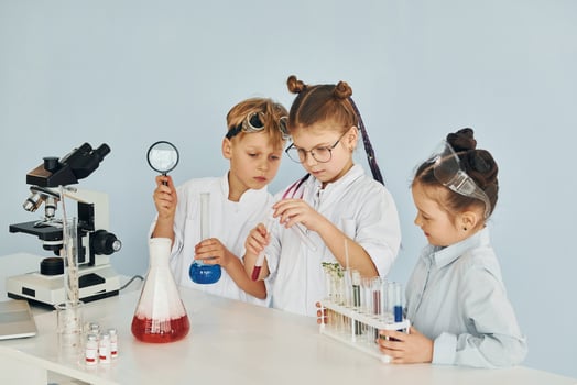 Children in white coats plays a scientists in lab by using equipment photo