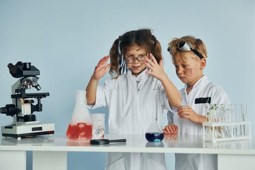 Little girl and boy in white coats plays a scientists in lab by using equipment photo