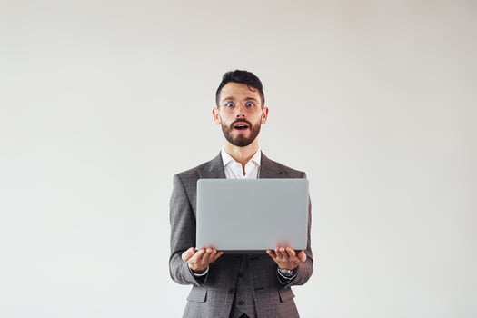 With laptop in hands. Young stylish businessman in suit indoors. Conception of success photo