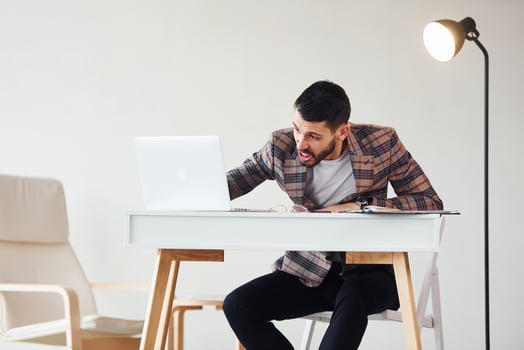 Uses laptop. Young stylish businessman in suit indoors. Conception of success photo