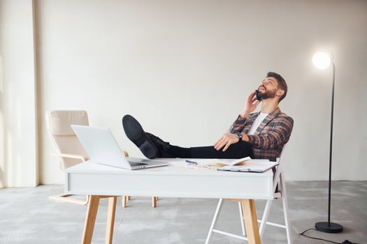 Have conversation by phone. Young stylish businessman in suit indoors. Conception of success photo
