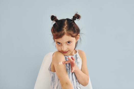 Cute little girl sits after vaccine injection indoors in hospital photo
