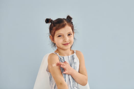 Cute little girl sits after vaccine injection indoors in hospital photo