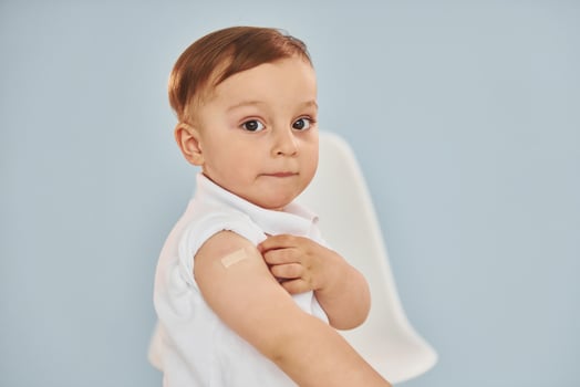 Cute little boy sits after vaccine injection indoors in hospital photo