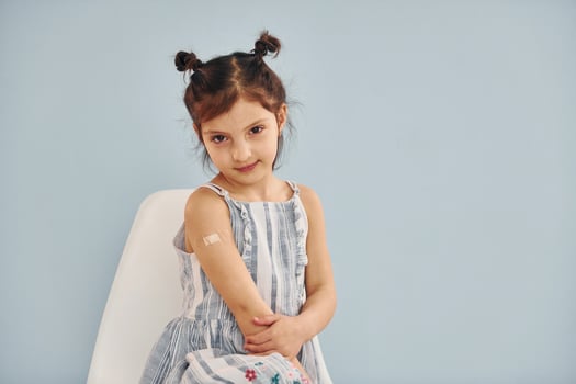 Cute little girl sits after vaccine injection indoors in hospital photo