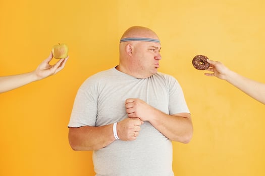 Apple or cookie. Funny overweight man in sportive head tie is against yellow background photo