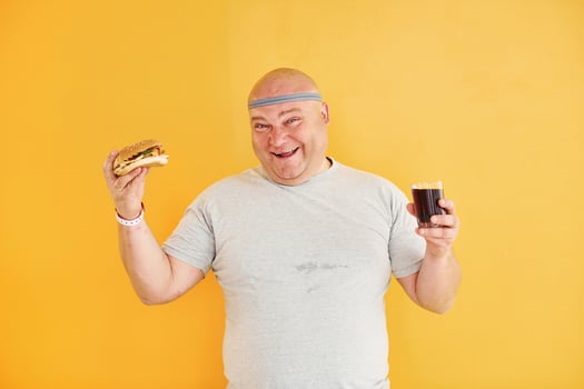 With fast food. Funny overweight man in sportive head tie is against yellow background photo