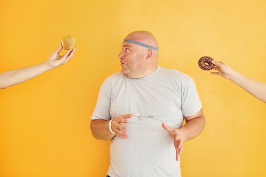 Apple or cookie. Funny overweight man in sportive head tie is against yellow background photo