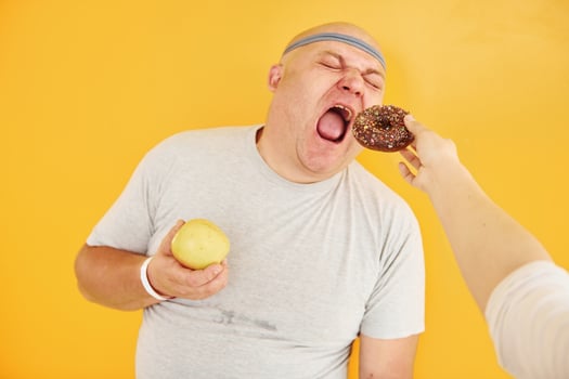 Apple or cookie. Funny overweight man in sportive head tie is against yellow background photo