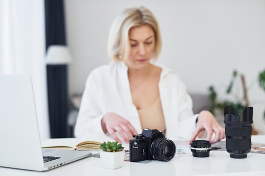 Middle-aged woman in elegant clothes is at home. Photographer with camera photo