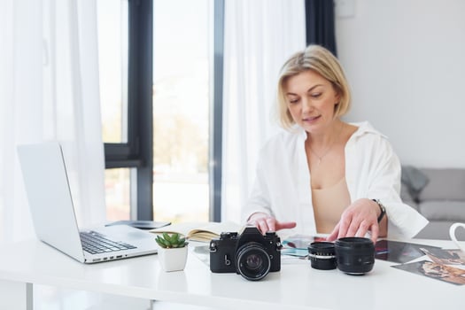 Middle-aged woman in elegant clothes is at home. Photographer with camera photo
