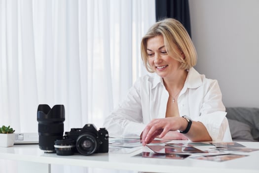 Middle-aged woman in elegant clothes is at home. Photographer with camera photo