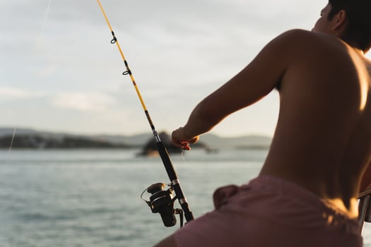 Fishing rod wheel closeup, man fishing with a beautiful sunset. photo