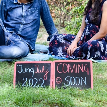 Indian couple posing for maternity baby shoot. The couple is posing in a lawn with green grass and the woman is falunting her baby bump in Lodhi Garden in New Delhi, India photo