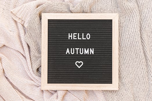 Autumnal Background. Black letter board with text phrase Hello Autumn lying on white knitted sweater. Top view, flat lay. Thanksgiving banner. Hygge mood cold weather concept photo
