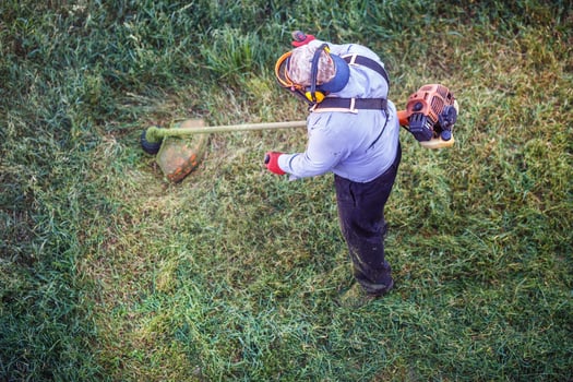 Top view fat dirty lawnmover man worker cutting dry grass with lawn mower. photo