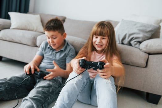 Sitting on the floor and playing videogame. Kids having fun in the domestic room at daytime together photo