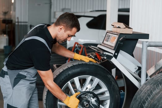 Taking the wheel. Man in uniform is working in the auto service photo