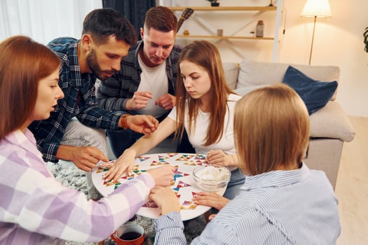 Focused at puzzle game. Group of friends have party indoors together photo