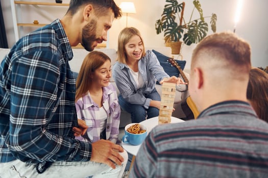 Focused on the tower building game. Group of friends have party indoors together photo