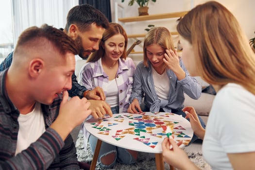 Puzzle game on the table. Group of friends have party indoors together photo