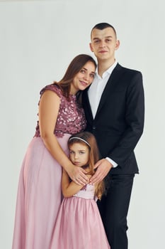 Happy couple with little daughter is standing in the studio photo