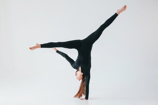 Professional exercises. Young woman in sportive clothes doing gymnastics indoors photo