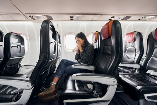 Feel sick. Young woman in casual clothes sits on the passenger seat in the plane photo