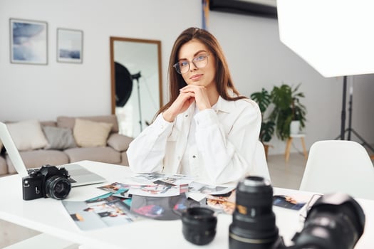 Female photographer in casual clothes is working indoors at daytime photo
