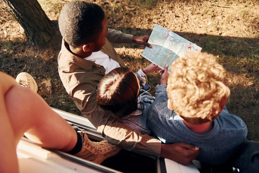 Holding map and looking for location. Group of young people is traveling together in the forest photo