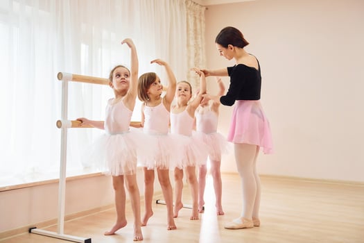 Coach teaches children. Little ballerinas preparing for performance by practicing dance moves photo