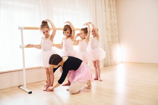 Working with coach. Little ballerinas preparing for performance by practicing dance moves photo