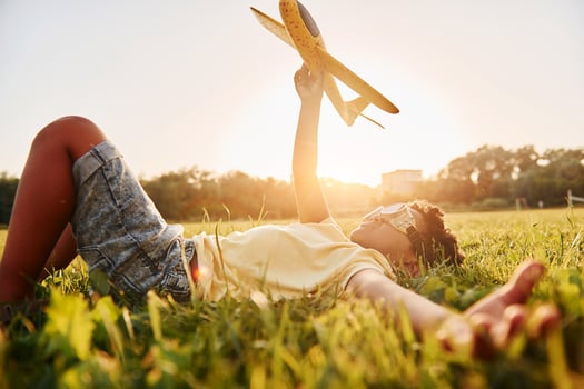 Boy with toy plane. African american kid have fun in the field at summer daytime photo