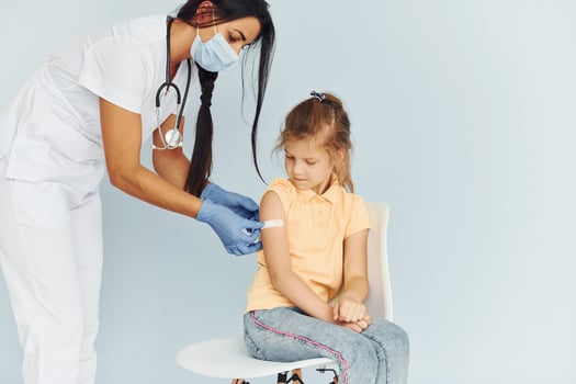 Doctor in uniform making vaccination to the little girl photo