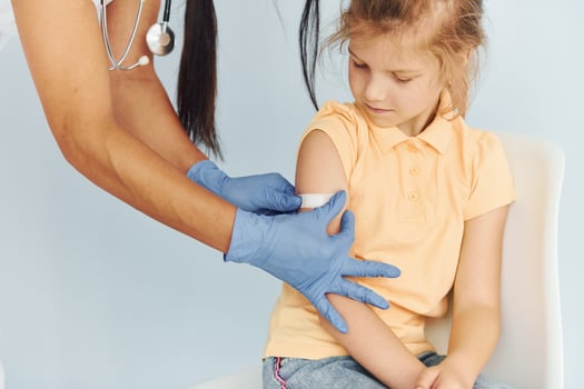Doctor in uniform making vaccination to the little girl photo