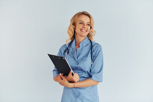 Holding documents. Young female doctor in uniform is indoors photo
