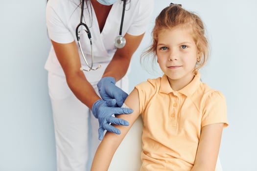 Cute little girl. Doctor in uniform making vaccination to the patient photo